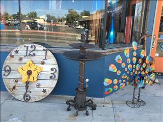 This pic is showing an outdoor clock and a steampunk bird bath , with a peacock and giraffe hanging (..)